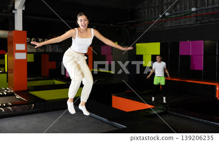 Girl acrobatic athlete jumping and exercising on trampoline indoors, modern hobby and fitness concept Girl acrobatic athlete jumping and exercising on trampoline indoors, modern hobby and fitness concept 139206235