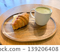 Croissant sandwich with cheese and ham served with green latte on tray. Breakfast meal, cafe serving, beverage pairing, and quick eating routine with simple ingredients. 139206408