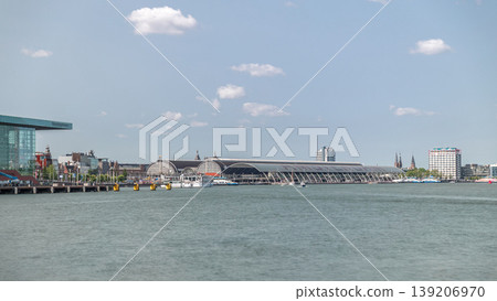 Panoramic view of Amsterdam Central Station with its curved roof and the Amstel River timelapse. Amsterdam, Netherlands Panoramic view of Amsterdam Central Station with its curved roof and the Amstel River timelapse. Amsterdam, Netherlands 139206970