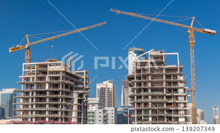 Aerial view of a skyscrapers under construction with huge cranes timelapse in Dubai. Aerial view of a skyscrapers under construction with huge cranes timelapse in Dubai. 139207349
