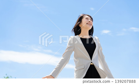 A woman/businesswoman standing outdoors under a blue sky. A woman/businesswoman standing outdoors under a blue sky. 139207888