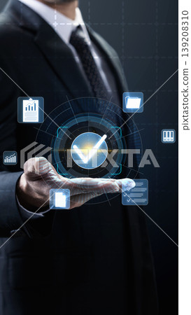 A professional businessman holds a digital holographic checkmark symbol surrounded by business data icons, representing success, quality control, and efficient document management A professional businessman holds a digital holographic checkmark symbol surrounded by business data icons, representing success, quality control, and efficient document management 139208310