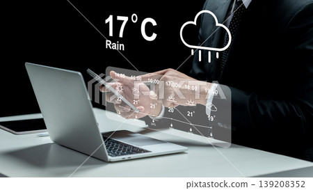 A businessman in a suit uses a laptop while a futuristic transparent digital interface displays a detailed weather forecast with temperature and rain icons 139208352