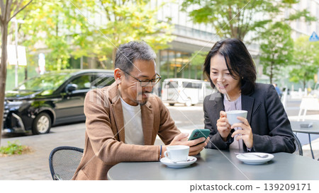 A couple ordering via mobile on the terrace A couple ordering via mobile on the terrace 139209171