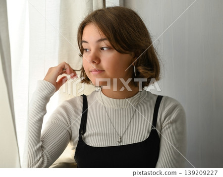 Portrait of a girl at the window in thought Portrait of a girl at the window in thought 139209227