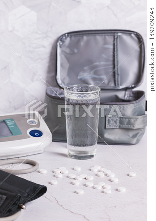 High blood pressure pills, a glass of water, and a tonometer on the table vertical view High blood pressure pills, a glass of water, and a tonometer on the table vertical view 139209243