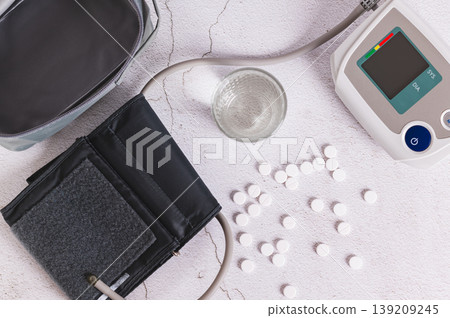 High blood pressure pills, a glass of water, and a tonometer on the table top view High blood pressure pills, a glass of water, and a tonometer on the table top view 139209245