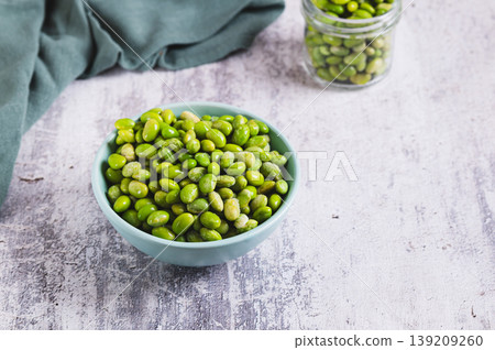Frozen edamame soybeans on a plate and in a jar on a table Frozen edamame soybeans on a plate and in a jar on a table 139209260