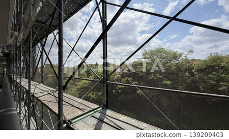 Scaffolding and protective netting for apartment building repairs and inspections. Scaffolding and protective netting for apartment building repairs and inspections. 139209403