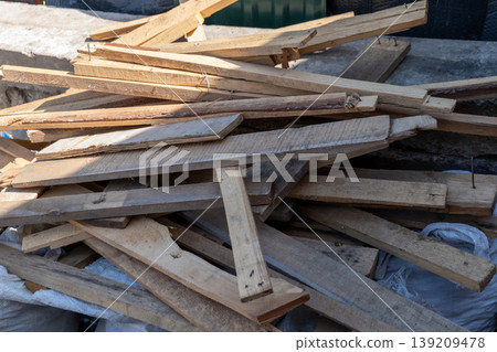 Scraps of wood are laid out in a pile at a building site where construction work takes place in bright sunlight Scraps of wood are laid out in a pile at a building site where construction work takes place in bright sunlight 139209478