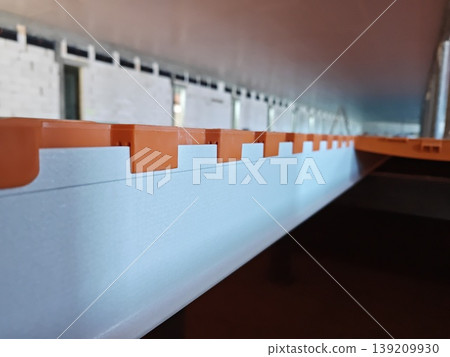 Side view of plastic slatted flooring panel mounted on support beam in pig housing system with visible structure detail. Livestock farming, agriculture equipment, construction Side view of plastic slatted flooring panel mounted on support beam in pig housing system with visible structure detail. Livestock farming, agriculture equipment, construction 139209930