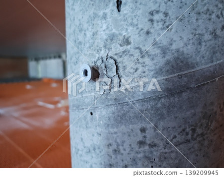 Close up of cracked concrete column with anchor fastener inside livestock building with plastic slatted flooring system. Construction detail, agriculture facility Close up of cracked concrete column with anchor fastener inside livestock building with plastic slatted flooring system. Construction detail, agriculture facility 139209945