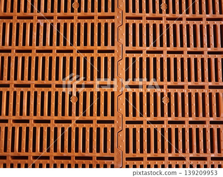 Orange plastic slatted floor panels for pig housing with perforated grid pattern and modular interlocking design. Livestock farming, agriculture equipment, animal housing Orange plastic slatted floor panels for pig housing with perforated grid pattern and modular interlocking design. Livestock farming, agriculture equipment, animal housing 139209953