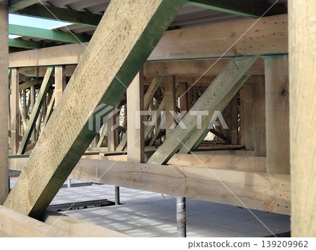 Wooden roof truss structure with diagonal braces and beams assembled on construction site in daylight. Construction, carpentry, architecture, engineering, housing development Wooden roof truss structure with diagonal braces and beams assembled on construction site in daylight. Construction, carpentry, architecture, engineering, housing development 139209962