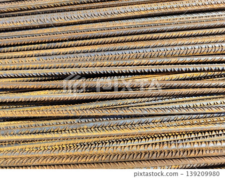 Rusted steel reinforcement bars stacked in dense horizontal layers with ribbed texture and oxidation on construction site. Building materials, metal industry, structural reinforcement Rusted steel reinforcement bars stacked in dense horizontal layers with ribbed texture and oxidation on construction site. Building materials, metal industry, structural reinforcement 139209980