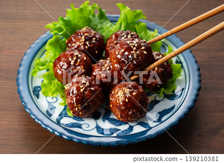 A glossy, shiny meatball in sweet and sour sauce, lifted with chopsticks (meatball, Japanese food, lifted with chopsticks) 139210381