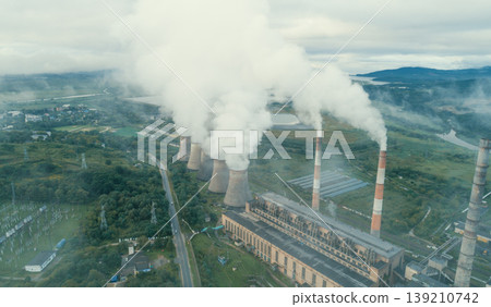 Industrial power plant actively releases large plumes of steam and smoke from its tall smokestacks and cooling towers into the sky Industrial power plant actively releases large plumes of steam and smoke from its tall smokestacks and cooling towers into the sky 139210742