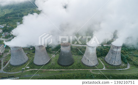 Industrial power plant with five massive cooling towers generating vast plumes of white steam into the air Industrial power plant with five massive cooling towers generating vast plumes of white steam into the air 139210751