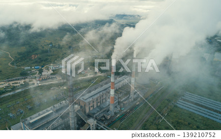 Industrial power plant actively releases large plumes of steam and smoke from its tall smokestacks and cooling towers into the sky Industrial power plant actively releases large plumes of steam and smoke from its tall smokestacks and cooling towers into the sky 139210752