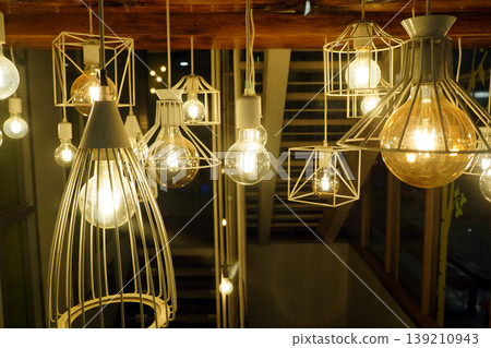 Group of decorative industrial pendant lights with glowing Edison bulbs, stylish modern interior lighting for cafe and home decor. 139210943