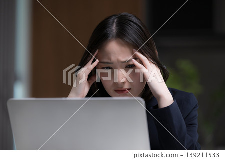一位女性正面臨著糟糕的商業環境：她很擔心，因為她失敗了，而且由於加班，她無法完成工作。 139211533