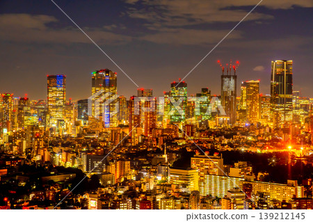 東京的摩天大樓和高聳的摩天大樓在夜色中熠熠生輝，景色迷人。 139212145