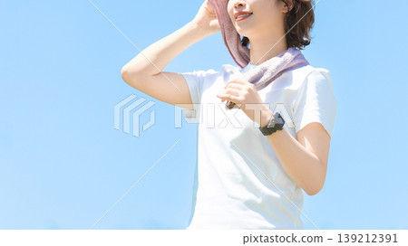 A woman in sports wiping sweat with a towel 139212391