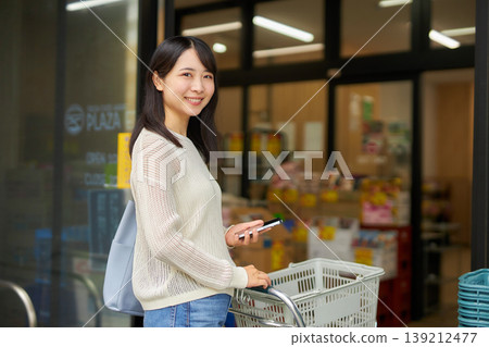 A young woman shopping with a shopping cart at a supermarket. 139212477
