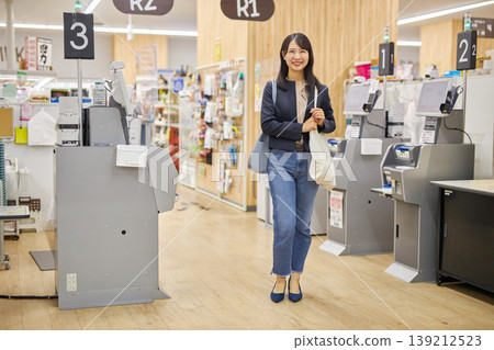 一位年輕女子在自助結帳機付款後，將環保袋挎在肩上。 139212523