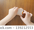 A child's hands begin folding a small orange piece of origami paper (educational, craft, challenge) 139212553