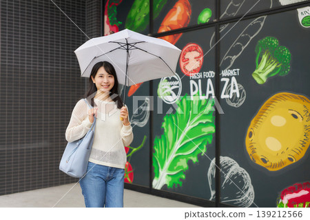 一位年輕女子撐著陽傘去超市。 139212566