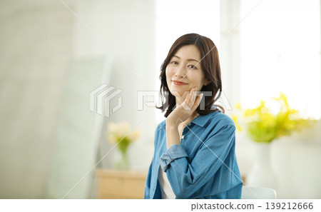 A middle-aged woman smiles at the camera in her living room. A middle-aged woman smiles at the camera in her living room. 139212666