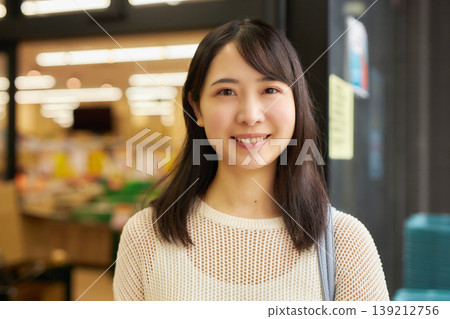 A young woman shopping with a shopping basket at a supermarket. A young woman shopping with a shopping basket at a supermarket. 139212756