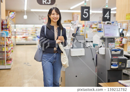 一位年輕女子在自助結帳機付款後，將環保袋挎在肩上。 139212782