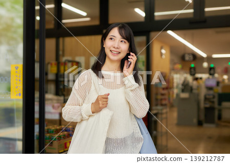 一位年輕女子在超市購物,手裡拿著一個環保袋。 一位年輕女子在超市購物,手裡拿著一個環保袋。 139212787