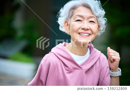 An active Japanese senior woman with a smile and clenched fist. 139212809