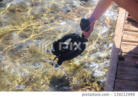 Woman cleaning her snorkeling mask in the clear blue sea, preparing for an exciting underwater adventure and enjoying the beauty of marine life Woman cleaning her snorkeling mask in the clear blue sea, preparing for an exciting underwater adventure and enjoying the beauty of marine life 139212999