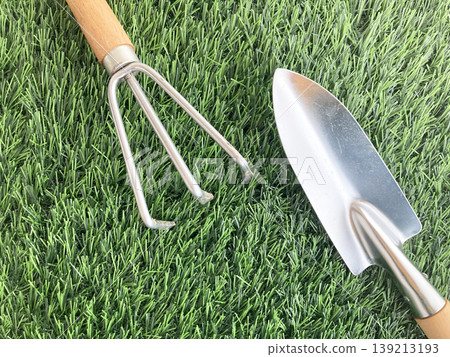 A gardening tool set consisting of a shovel and a rake lined up on the lawn - for maintaining a home vegetable garden. A gardening tool set consisting of a shovel and a rake lined up on the lawn - for maintaining a home vegetable garden. 139213193