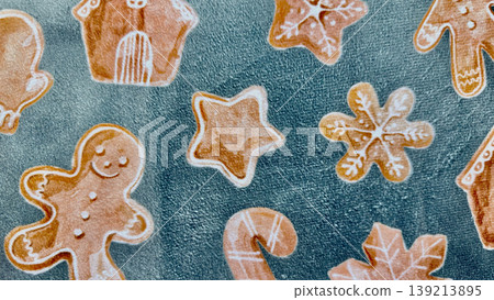 gingerbread cookie assortment in whimsical holiday shapes scattered on textured teal fabric evoking cozy christmas cheer 139213895