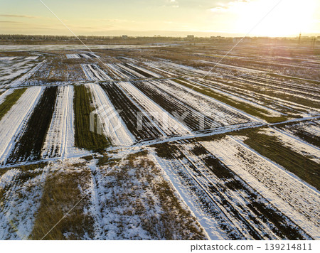 Top view of empty snowy fields patched landscape, dark horizon and bright sky on sunny winter day. Aerial drone photography concept. 139214811