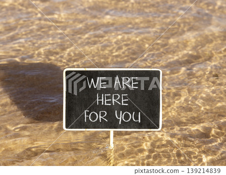 Support, help and we are here for you symbol. Concept words We are here for you on beautiful blackboard. Beautiful Red sea water background. Business we are here for you concept. Copy space. 139214839