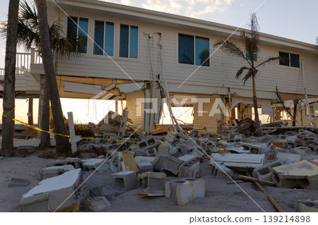 Storm surge caused by hurricane wind severe damaged residential houses on ocean shore. Natural disaster consequences in Florida Storm surge caused by hurricane wind severe damaged residential houses on ocean shore. Natural disaster consequences in Florida 139214898
