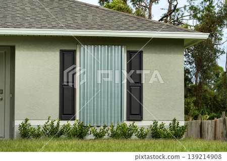 Steel panels mounted over house windows in Florida to shield against hurricane damage. Storm preparation and home protection Steel panels mounted over house windows in Florida to shield against hurricane damage. Storm preparation and home protection 139214908