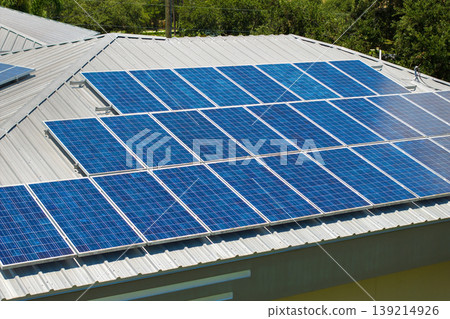 Solar panels on residential house rooftop. Photovoltaic sells for producing of clean electrical energy in suburban rural area. Concept of investment in autonomous home Solar panels on residential house rooftop. Photovoltaic sells for producing of clean electrical energy in suburban rural area. Concept of investment in autonomous home 139214926