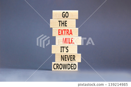 Go the extra mile symbol. Concept words Go the extra mile. It's never crowded on beautiful wooden blocks. Beautiful grey paper background. Business go the extra mile concept. Copy space. Go the extra mile symbol. Concept words Go the extra mile. It's never crowded on beautiful wooden blocks. Beautiful grey paper background. Business go the extra mile concept. Copy space. 139214985