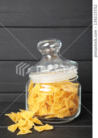 Raw farfalle pasta on glass jar on black background. Vertical photo Raw farfalle pasta on glass jar on black background. Vertical photo 139215552