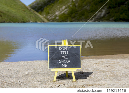 Tell or show symbol. Concept words Do not tell me, show me on beautiful black blackboard. Beautiful mountain lake background. Business tell or show concept. Copy space. 139215656