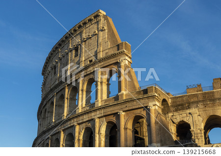 Famous Coliseum in Rome. Colosseum, or Coliseum. Sunset at huge Roman amphitheatre, Rome, Italy, Europe. Famous touristic place in the world and Europe. Beautiful blue sky background. Famous Coliseum in Rome. Colosseum, or Coliseum. Sunset at huge Roman amphitheatre, Rome, Italy, Europe. Famous touristic place in the world and Europe. Beautiful blue sky background. 139215668
