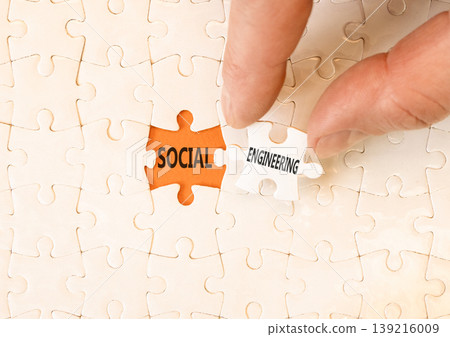 Social engineering words symbol. Concept words Social engineering on beautiful white puzzles. Beautiful orange background. Businessman hand. Business and Social engineering words concept. Copy space. 139216009