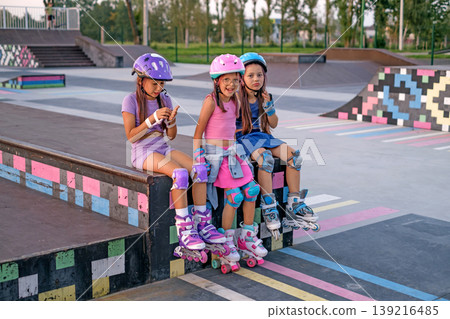 A group of children relax on the sports ramp after roller skating. A skate park for professional sports training in skateboarding 139216485